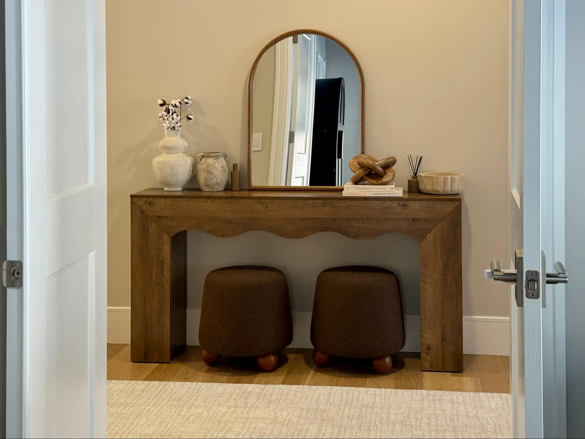 Entryway console table with arched mirror and textured ottomans